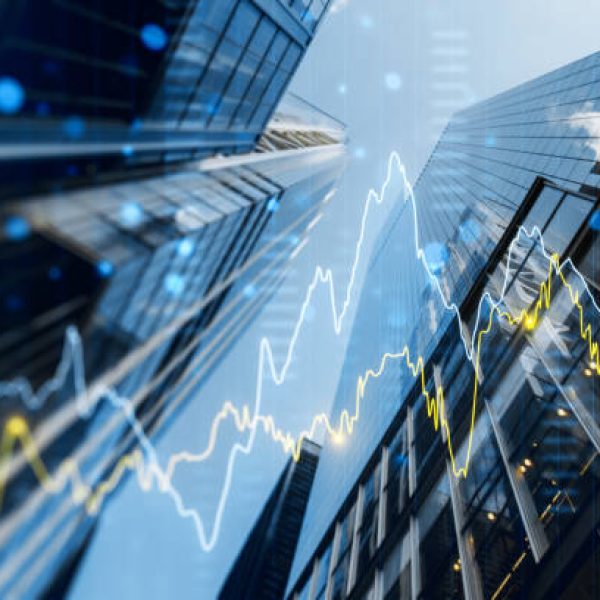 A double exposure image of skyscrapers with overlay of financial graphs, set against a blurred background, illustrating the concept of business growth